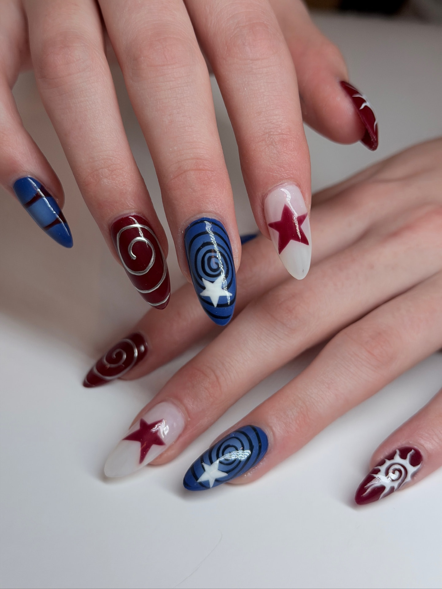 Blume Nail Bar - Luxury Nail Salon — almond nails with starry spirals in cobalt blue and cherry red